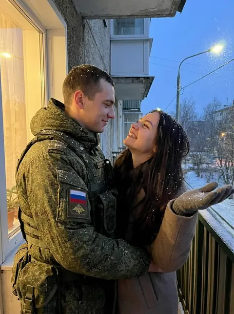 Военный в форме пиксель обнимает девушку на балконе, она ловит снежинки ладонью промт для нейросети